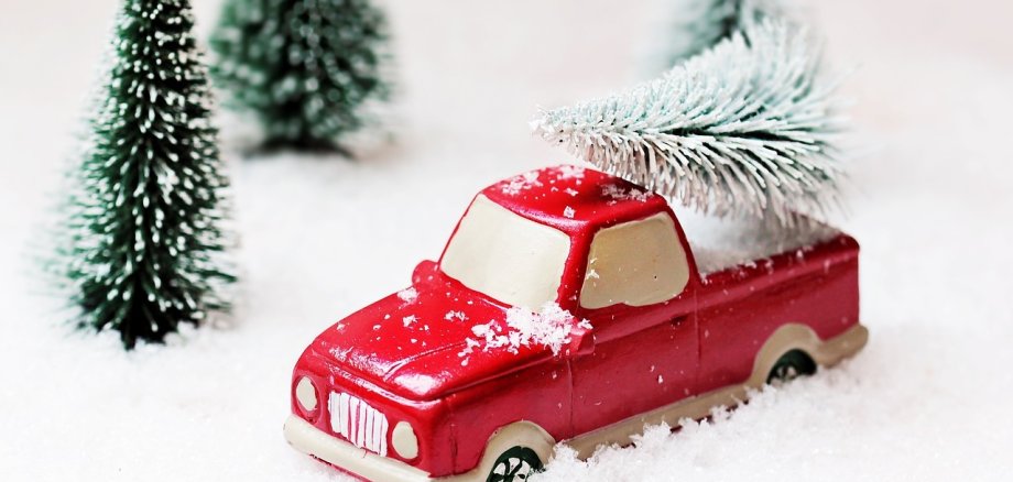 Spielzeugauto in Schneelandschaft hat Weihnachtsbaum geladen
